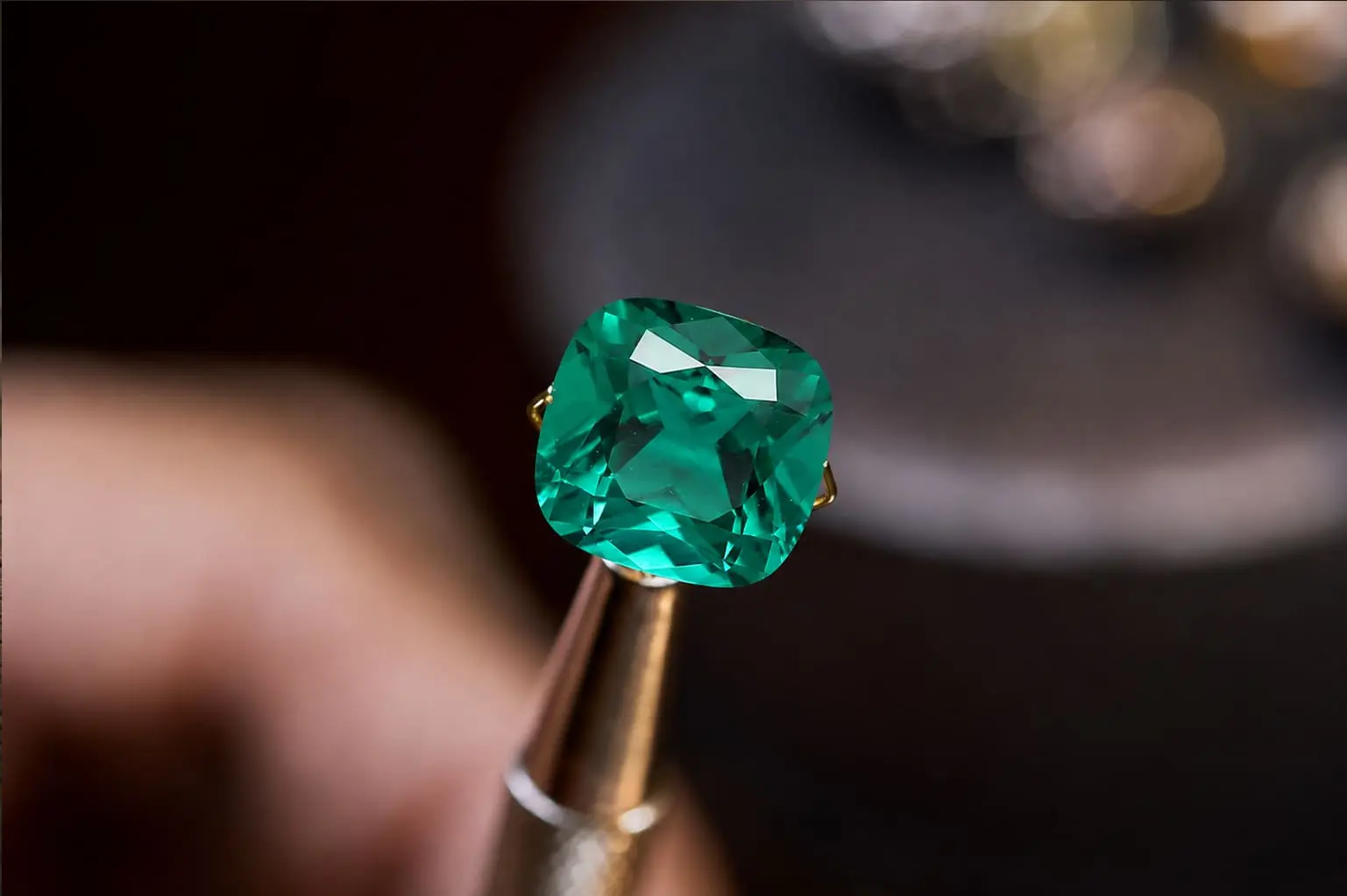 Gema verde facetada sujetada con unas pinzas durante la inspección